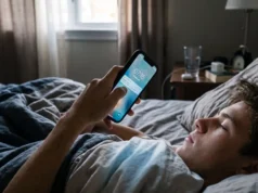 Mano sosteniendo un teléfono encendido en la oscuridad de una recámara al amanecer