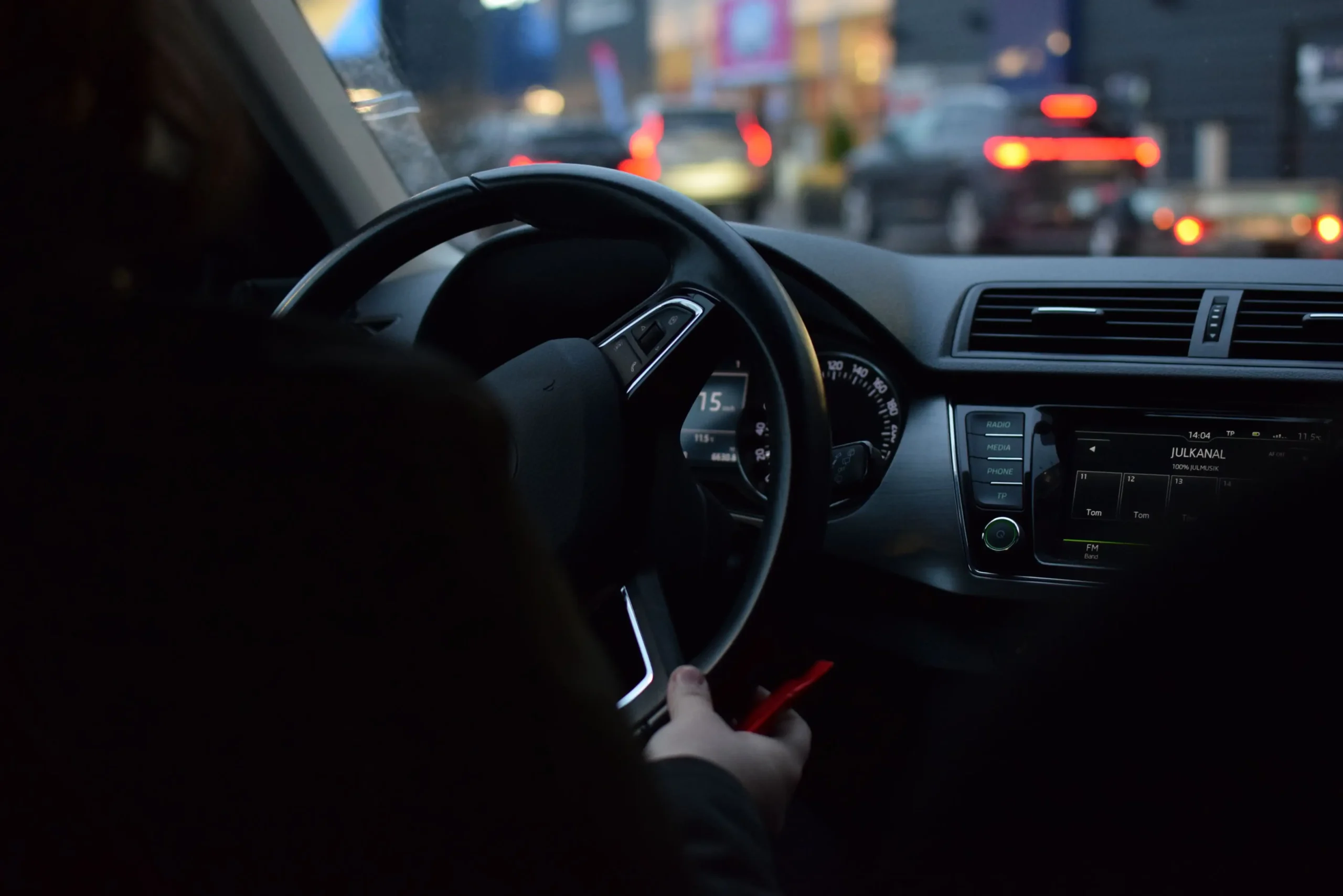 Conductor de aplicación revisa su celular dentro de su auto estacionado en una calle de Ciudad de México.