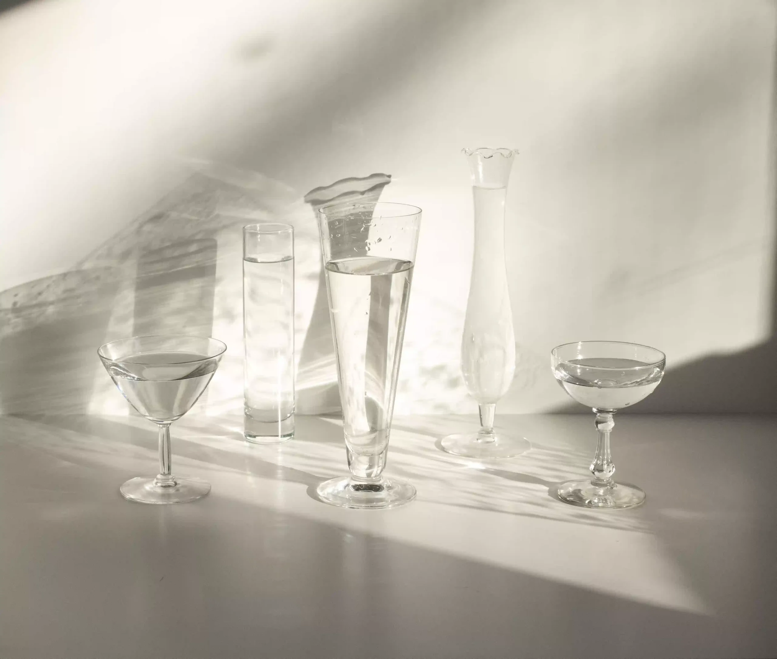 Varias copas con agua natural y mineral alineadas sobre una mesa de cata en un restaurante